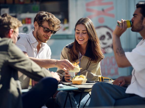 Young people sitting outside eating together Young people sitting outside eating together