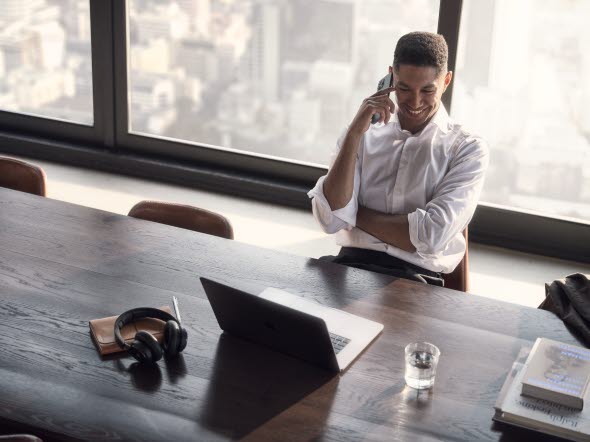 Picture of a man talking on his mobile phone in front of a laptop Picture of a man talking on his mobile phone in front of a laptop