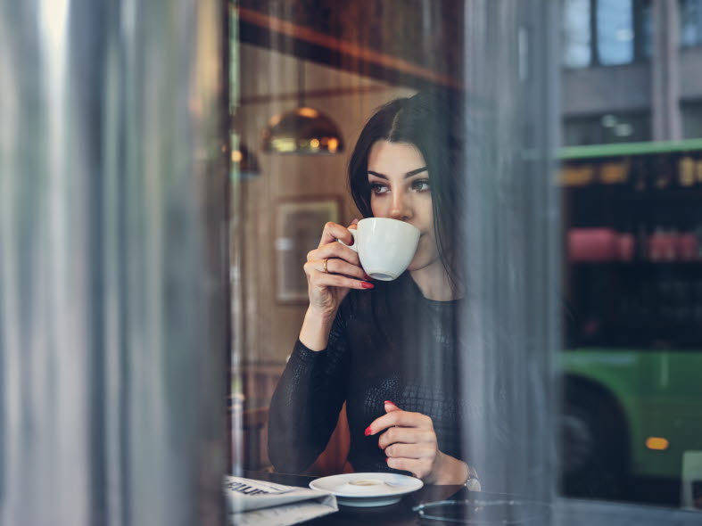 Woman having a coffee looking out the window at a café