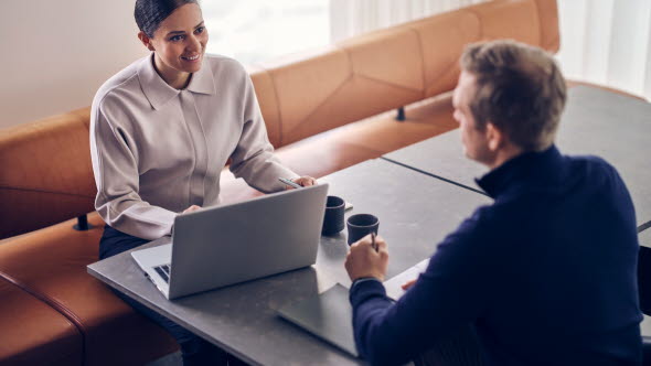 Woman with laptop and man sitting at a table across each other